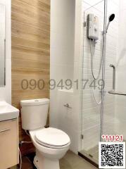 Modern bathroom interior with a white ceramic toilet, electric shower unit, and wooden paneling