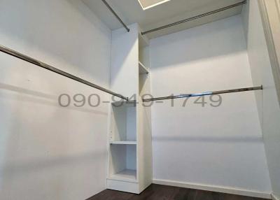 Empty walk-in closet with built-in shelves and wooden flooring