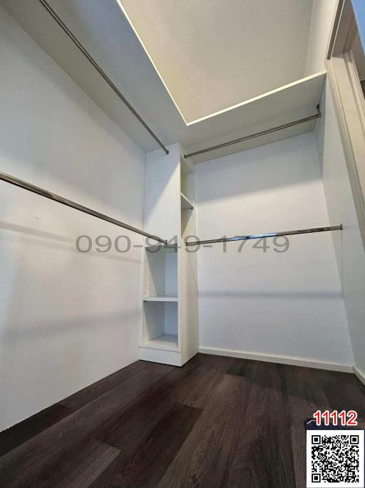 Empty walk-in closet with built-in shelves and wooden flooring