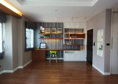 Modern home office with wooden floors, desk, and shelving units