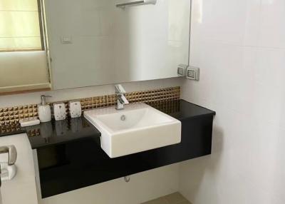 Modern bathroom with a rectangular sink, black countertop, and decorative mosaic tile backsplash