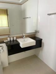 Modern bathroom with a rectangular sink, black countertop, and decorative mosaic tile backsplash