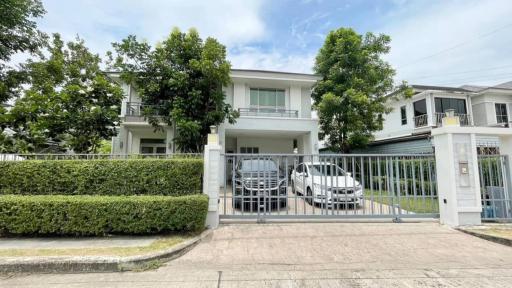 Modern two-story residential house with a gated entrance and vehicles parked in the driveway