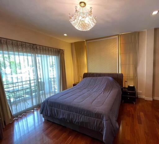 Spacious bedroom with wooden floor and elegant chandelier