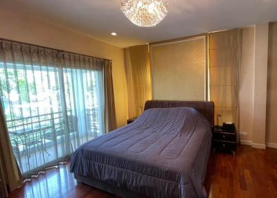 Spacious bedroom with wooden floor and elegant chandelier