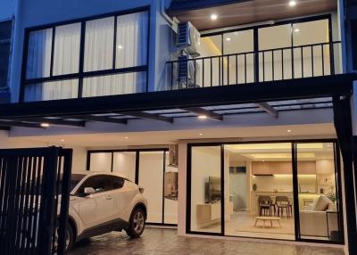 Modern two-story house exterior at dusk with illuminated interiors and a car parked outside