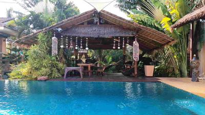 Tropical styled backyard with a swimming pool and a thatched gazebo