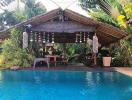 Tropical styled backyard with a swimming pool and a thatched gazebo