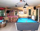 Spacious entertainment room with pool table, bar area, and lounge seating