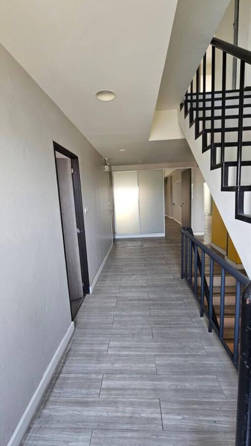 Bright and spacious hallway with modern flooring and black railing