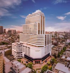 Modern high-rise building exterior against a blue sky with clouds