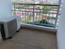 Compact balcony with air conditioning unit and a view of the cityscape