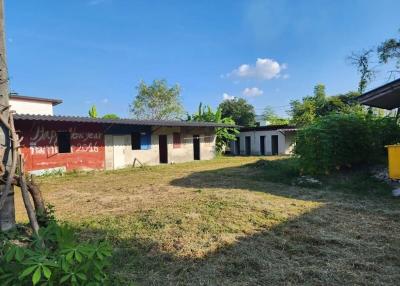 View of a property with a spacious lawn and a long single-story building with metal roofing