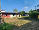 View of a property with a spacious lawn and a long single-story building with metal roofing