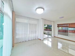 Spacious and well-lit living room with large windows and tiled flooring