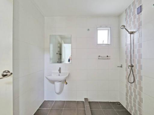 Modern white tiled bathroom with a walk-in shower and window