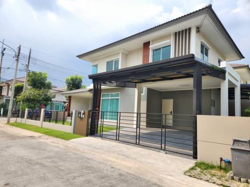 Modern two-story house with carport and paved driveway in a residential neighborhood