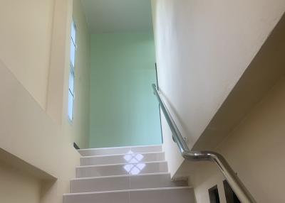 Bright staircase with large window and white railings inside a home