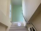 Bright staircase with large window and white railings inside a home