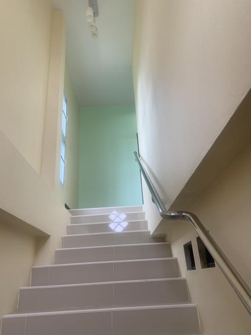 Bright staircase with large window and white railings inside a home