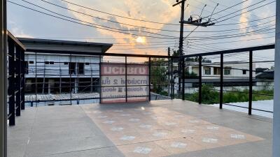 Wide angle view of a building exterior at dusk with commercial signage and a spacious terrace