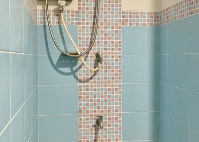 A tiled bathroom shower area with an electric shower head