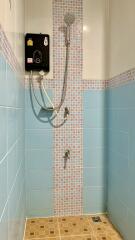 A tiled bathroom shower area with an electric shower head