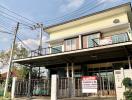 Two-story residential house with balcony and gated entrance