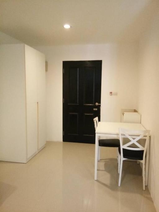 Compact building interior with white walls and a small table by the door