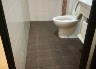 Compact bathroom with brown floor tiles and wall-mounted toilet