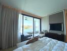 Bright and airy bedroom with waterfront view, ceiling fan, and large television