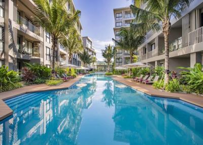 Luxurious residential building complex with outdoor swimming pool surrounded by palm trees and sun loungers