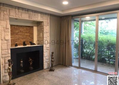Spacious living room with stone fireplace and large glass door leading to balcony