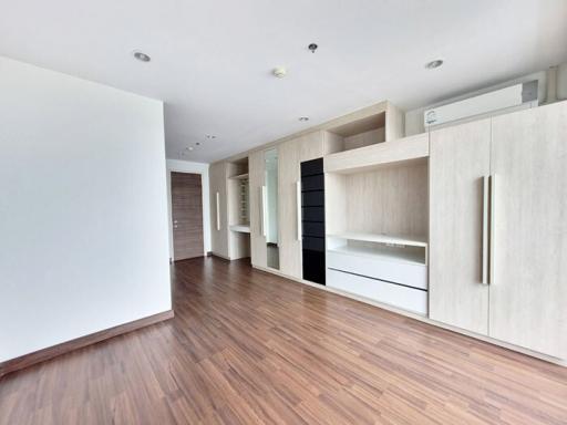 Spacious modern living room with wooden flooring and built-in shelving units