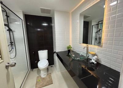Modern bathroom with glass sink, shower, and white tiles