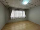 Bright and empty bedroom with large window and wooden floor