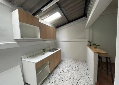 Compact modern kitchen with terrazzo flooring and wooden accents