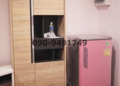 Compact bedroom with wooden wardrobe and pink refrigerator