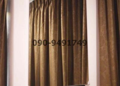 Partial view of a window with curtains and a mirror reflecting the curtains