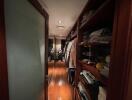 Dimly lit hallway with wooden flooring and built-in storage shelves