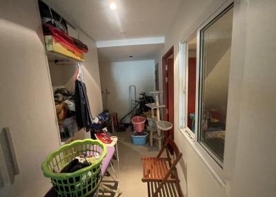 Cluttered laundry room with storage space, natural light from windows, and tiled flooring