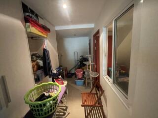 Cluttered laundry room with storage space, natural light from windows, and tiled flooring