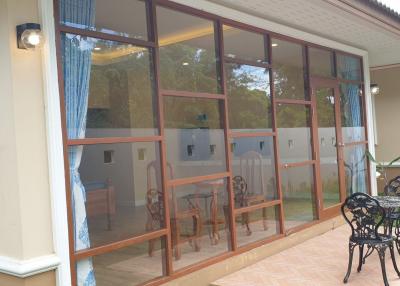 Spacious patio with large glass windows and doors leading to the interior of the house, featuring an outdoor seating area