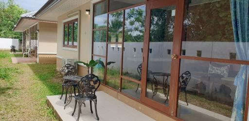 Front view of a house with large windows and outdoor sitting area