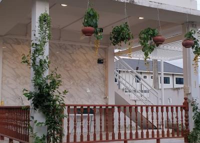 Exterior view of a house with a porch, hanging plants, and staircase