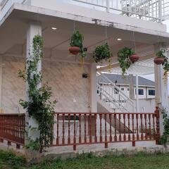 Exterior view of a house with a porch, hanging plants, and staircase