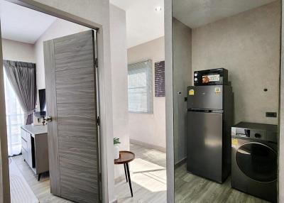 Modern Apartment Interior with Open Door Leading to Bedroom, Washer, and Refrigerator