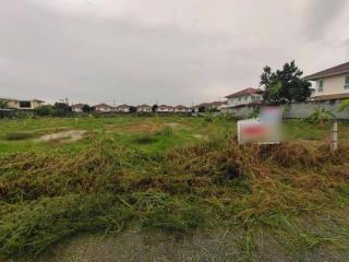 Empty residential building lot with overgrown grass and cloudy sky