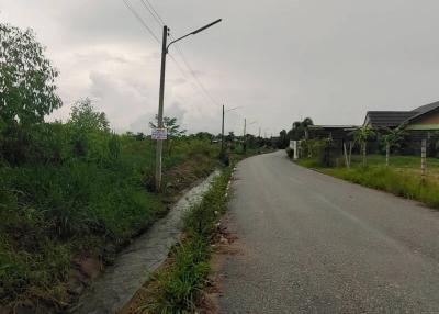 Paved road with street signs and residential buildings alongside under overcast sky