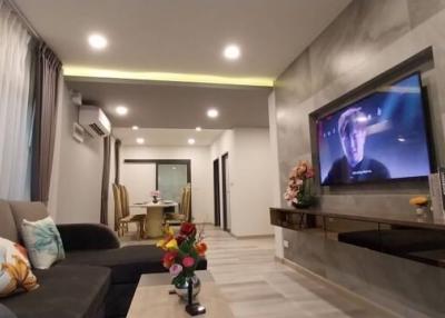 Modern living room with cozy design, featuring a comfortable sofa, a mounted television, and ambient lighting
